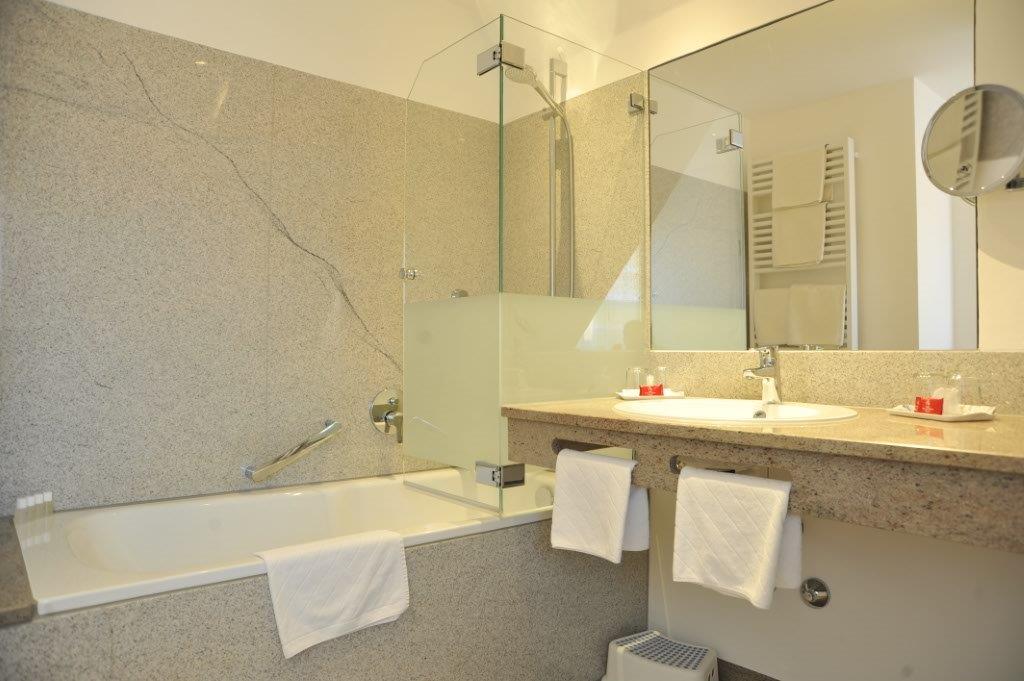 Bathroom with bath and glass screen, washbasin with mirror, towels and heated towel rail