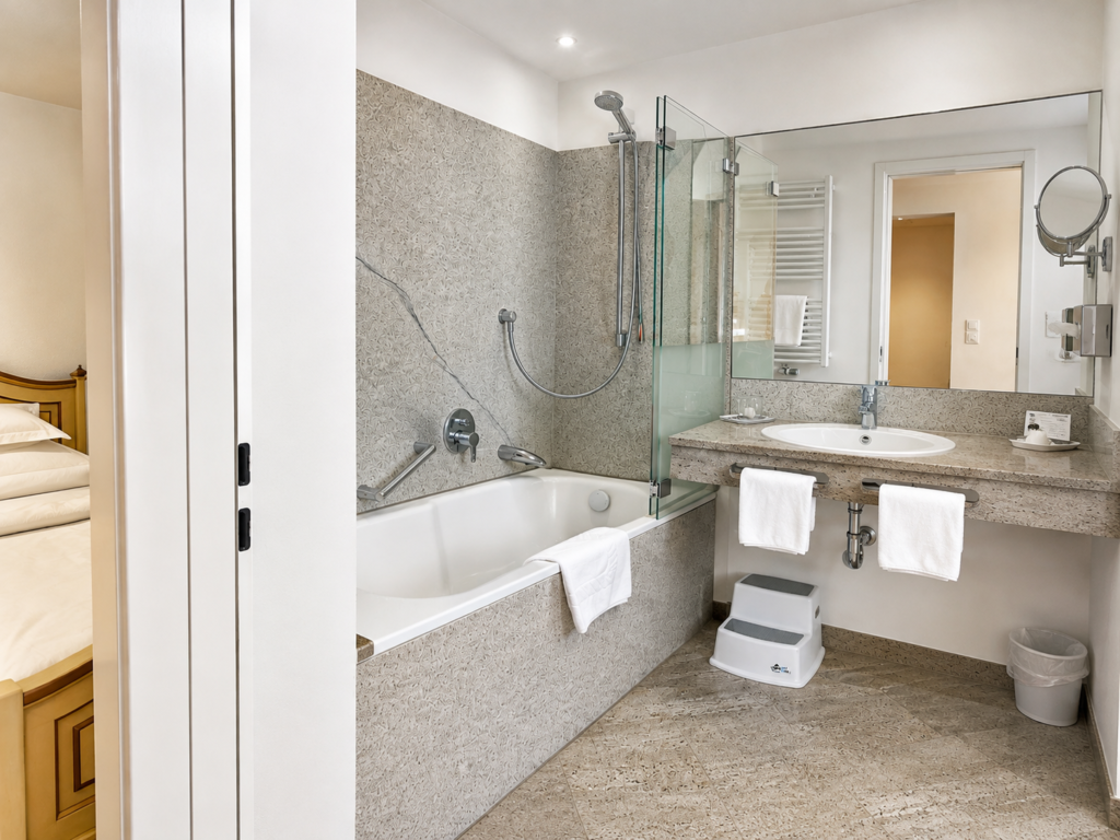 Bathroom with bath, glass screen, stone washbasin with a large mirror and towels