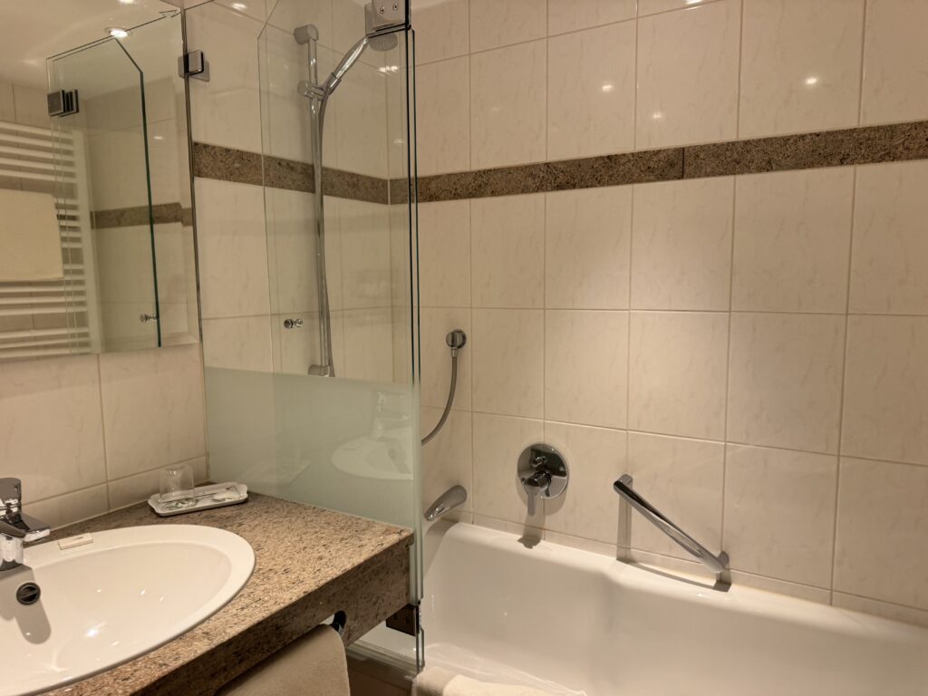 Bathroom with washbasin, mirror and a bath with a glass screen