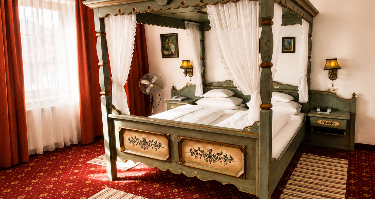 Himmelbett aus grün bemaltem Holz mit weißen Vorhängen, Nachttischen mit Wandleuchten und rotem Teppichboden