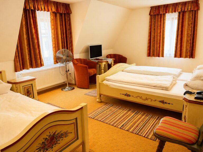 Triple Room with painted beds, armchairs and orange curtains