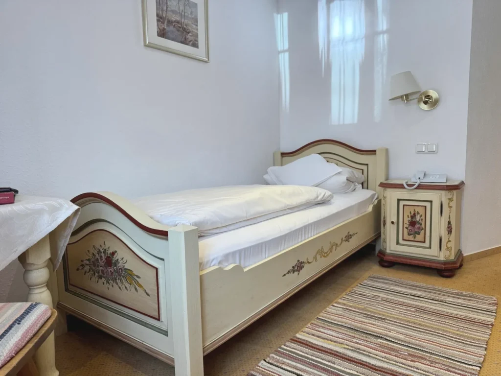Painted single bed with a flower motif on the footboard and a matching bedside table with a telephone