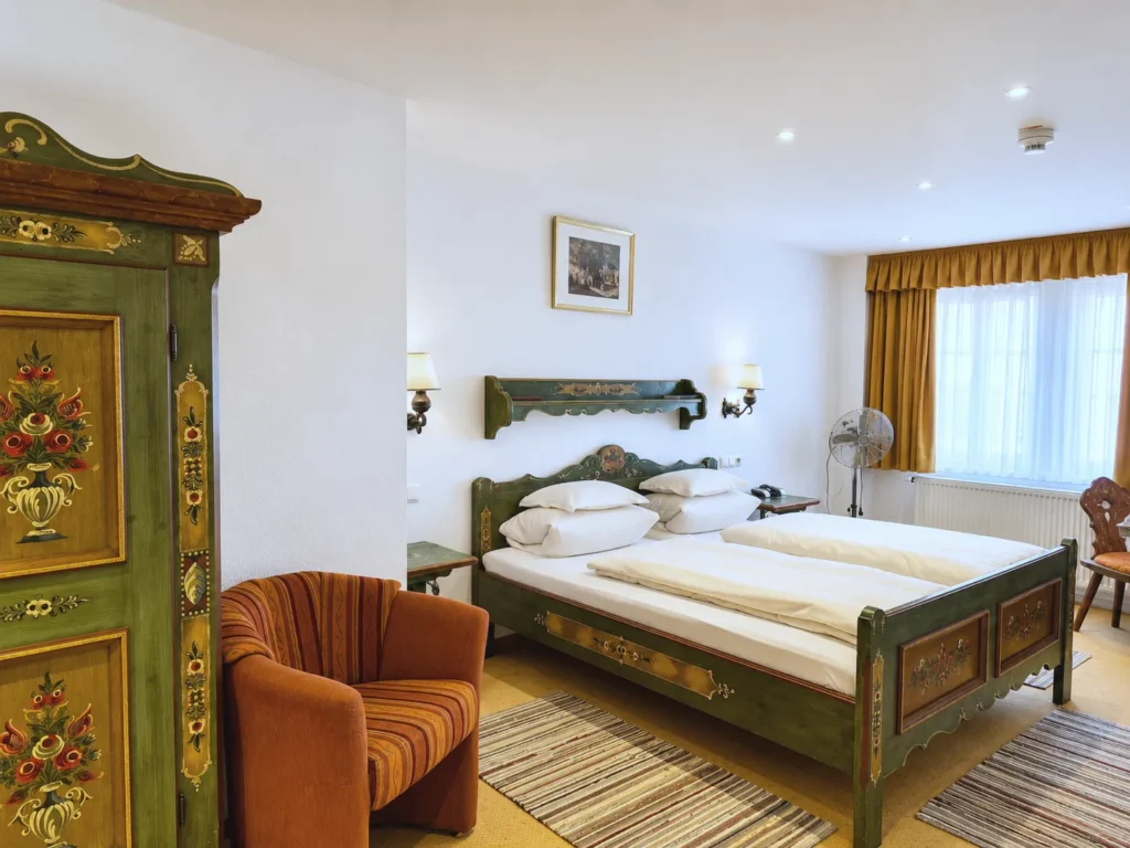 Double Room with a painted farmhouse wardrobe, a striped armchair and a green double bed with floral decoration